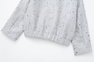 Detailed close-up of silver sequined tweed jacket cuffs and elastic hem texture