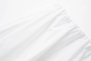 Détail de la taille élastique avec tissu plissé et coutures fines sur une robe midi blanche