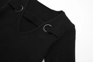 Detail of V-neckline on black knit dress with decorative horizontal strap and metal buckles