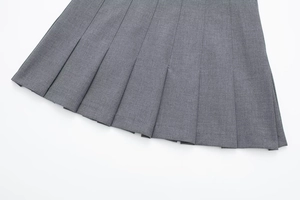 Detailed macro view showing the precise pleats and gray fabric texture of the skirt