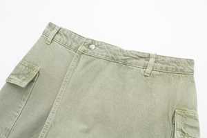 Vue macro détaillée de la texture sergé de coton kaki et du bouton métallique sur la jupe