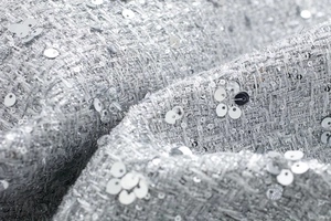 Macro detail of high-grade silver tweed fabric with shimmering metallic sequins decoration