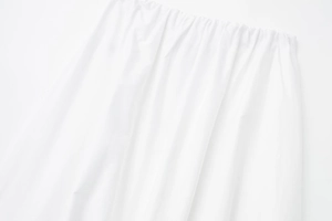 Gros plan détaillé de la taille élastique et de la texture plissée sur la jupe midi blanche