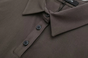 Dettaglio di un abito a polo marrone con colletto classico e tre bottoni neri