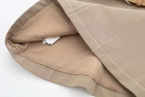Detailed macro view of khaki garment interior showing white lining and contrast stitching