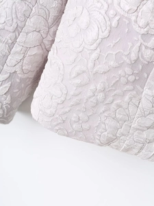 Macro shot of 3D floral jacquard texture and hem stitching on light purple blazer