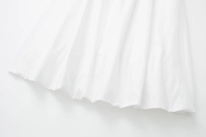 Gros plan sur un tissu tissé blanc léger montrant les détails de l'ourlet minimaliste