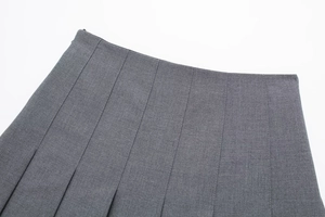 Detail of the high waist cut and invisible side zipper on a grey pleated mini skirt