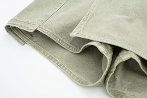 Gros plan sur un tissu sergé vert clair montrant des coutures doubles et une texture