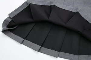Detail of grey pleated mini skirt featuring thick twill fabric and black inner lining