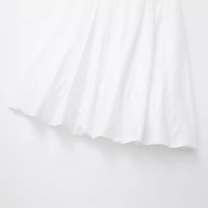 Jupe midi blanche fluide avec plis élégants et tissu léger pour un look printanier minimaliste