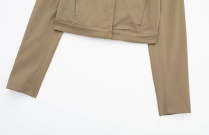 Détail d'une veste courte kaki montrant des coutures fines et la texture du sergé