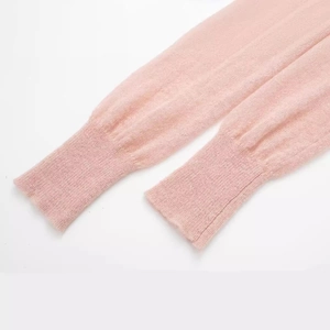 Close-up of soft light pink knitted long sleeve top with ribbed cuffs and fuzzy texture