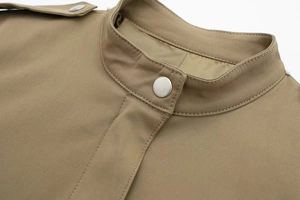 Détail de la veste kaki montrant le col montant, le bouton pression et l'épaulette