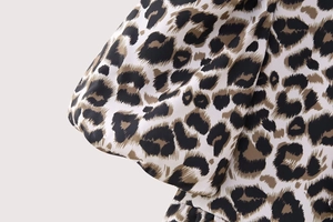 Detail of trendy leopard print top featuring elegant puff sleeves and textured woven fabric