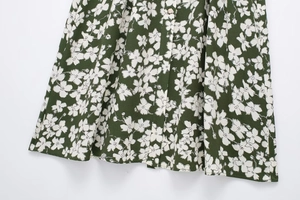 Detailed macro view of dark green floral dress hem with buttons and crepe fabric texture