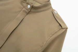 Détail de la veste kaki avec col montant, boutons-pression argentés et texture de tissu sergé