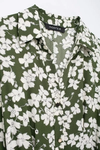 Detail showing the floral print dark green shirt collar with elegant golden buttons