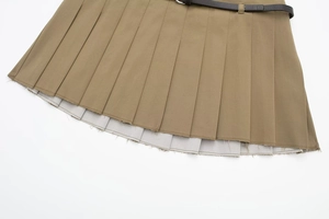 Détail d'une jupe-short plissée kaki avec ourlet brut et ceinture noire à boucle