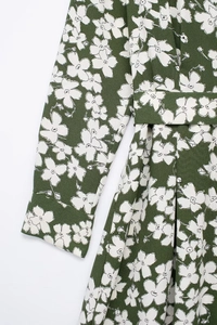 Detailed macro view of dark green floral crepe fabric texture and waist tie on the dress