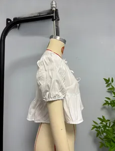 Detail of white puff sleeve blouse with lace-up neckline and pleated peplum hemline