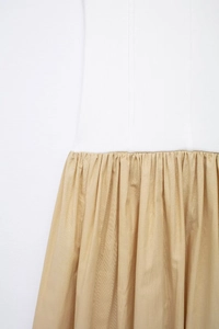 Close-up of white ribbed knit fabric stitched with champagne pleated chiffon detail