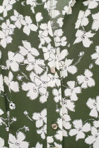 Macro detail of dark green floral print fabric with champagne gold metal buttons