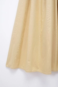Close-up detail of champagne gold pleated dress fabric with silky texture and fine stitching