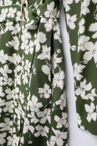 Close-up of floral print dress fabric texture with green base and white flower patterns