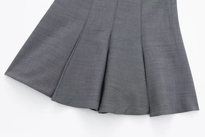Close-up of the pleated hemline detail on a dark grey skater dress in premium suit fabric