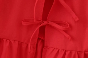 Close-up of red bubble sleeve top with lace-up bow and pleated ruffle waist details