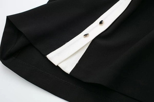 Dettaglio del tessuto in crepe nero con profili bianchi a contrasto e bottoni dorati