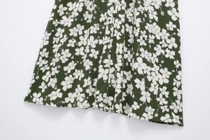 Close-up of floral print dress hem with precise stitching on green woven fabric