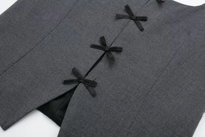 Detail of grey twill top featuring three delicate black ribbon bows on side slit hem