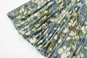 Détail de la jupe plissée à imprimé floral en mousseline verte, bleue et jaune