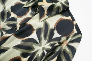 Détail du col de chemise à motifs avec boutons métalliques et imprimé floral abstrait