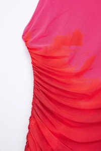 Detail of red ombre mesh dress featuring side ruching and vibrant gradient texture
