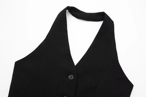 Detail of black halter vest showing deep V-neckline and smooth woven fabric texture