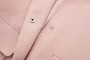 Dettaglio della giacca bomber rosa chiaro con trama in twill e bottone a pressione