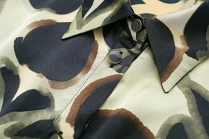 Gros plan d'une robe en satin à motifs géométriques avec col pointu et boutons métalliques