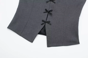 Detailed close-up of dark grey halter top featuring three black bow tie decorations
