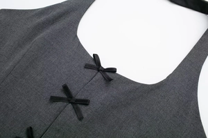 Detail of dark grey halter top featuring three black satin bows on suit fabric texture