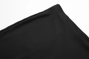 Detailed macro view of the premium black satin fabric stitching on the midi skirt waist