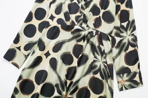 Détail du col en V boutonné sur robe verte à motifs géométriques et floraux