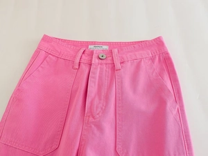Detail of high-waisted pink straight leg cargo pants with large front pockets and premium denim