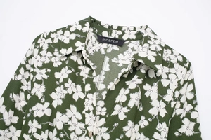 Close-up of green floral chiffon fabric with delicate white flower print and turn-down collar