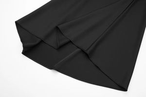 Detail of a black satin midi skirt showing smooth silk texture and fine curved hemline