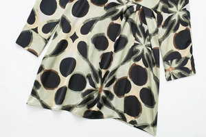 Détail d'une robe en satin vert gris avec imprimé floral géométrique et nœud à la taille