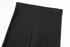 Detailed macro view of the black midi skirt waist and textured satin fabric weave