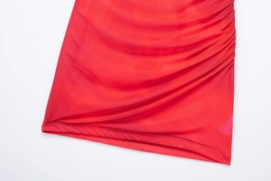 Detailed close-up of ruched orange-red mesh fabric with pleated side sewing on a dress